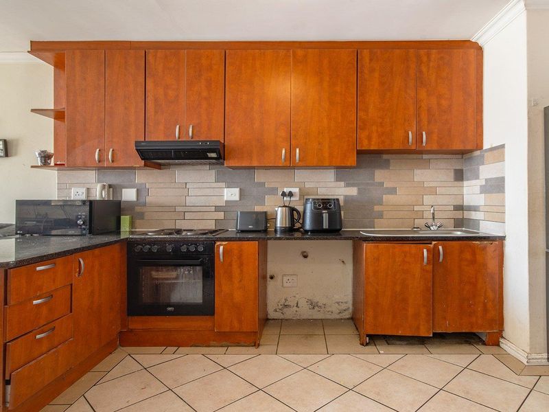Kitchen featuring wooden cabinetry, granite countertops, built-in oven, and tiled backsplash. Requires maintenance to address cabinet and wall damage.