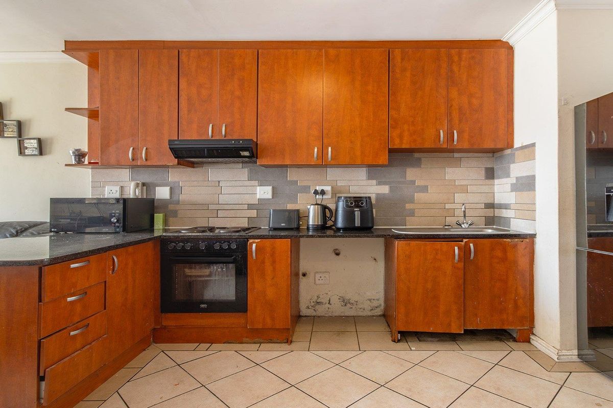 Kitchen featuring wooden cabinetry, granite countertops, built-in oven, and tiled backsplash. Requires maintenance to address cabinet and wall damage.