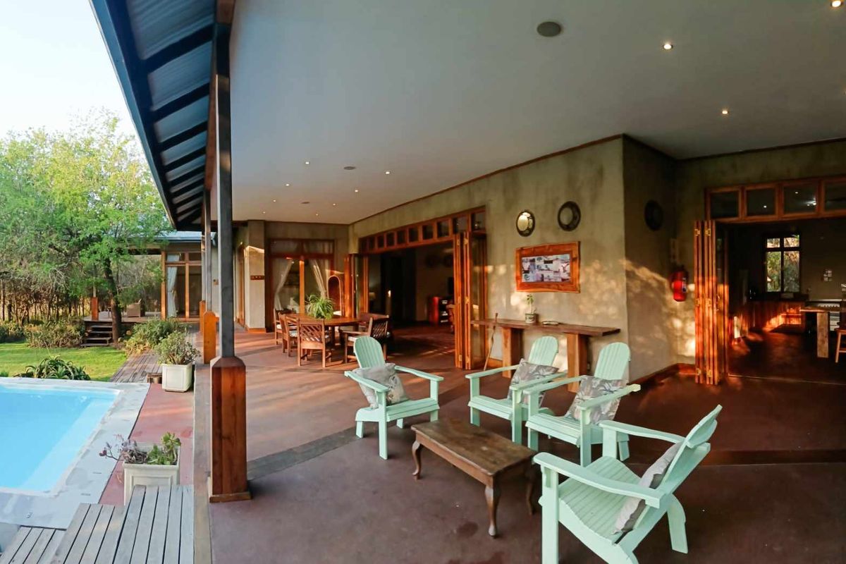 Spacious covered patio area featuring bi-fold doors leading to the interior, recessed lighting, and direct access to an adjacent swimming pool.