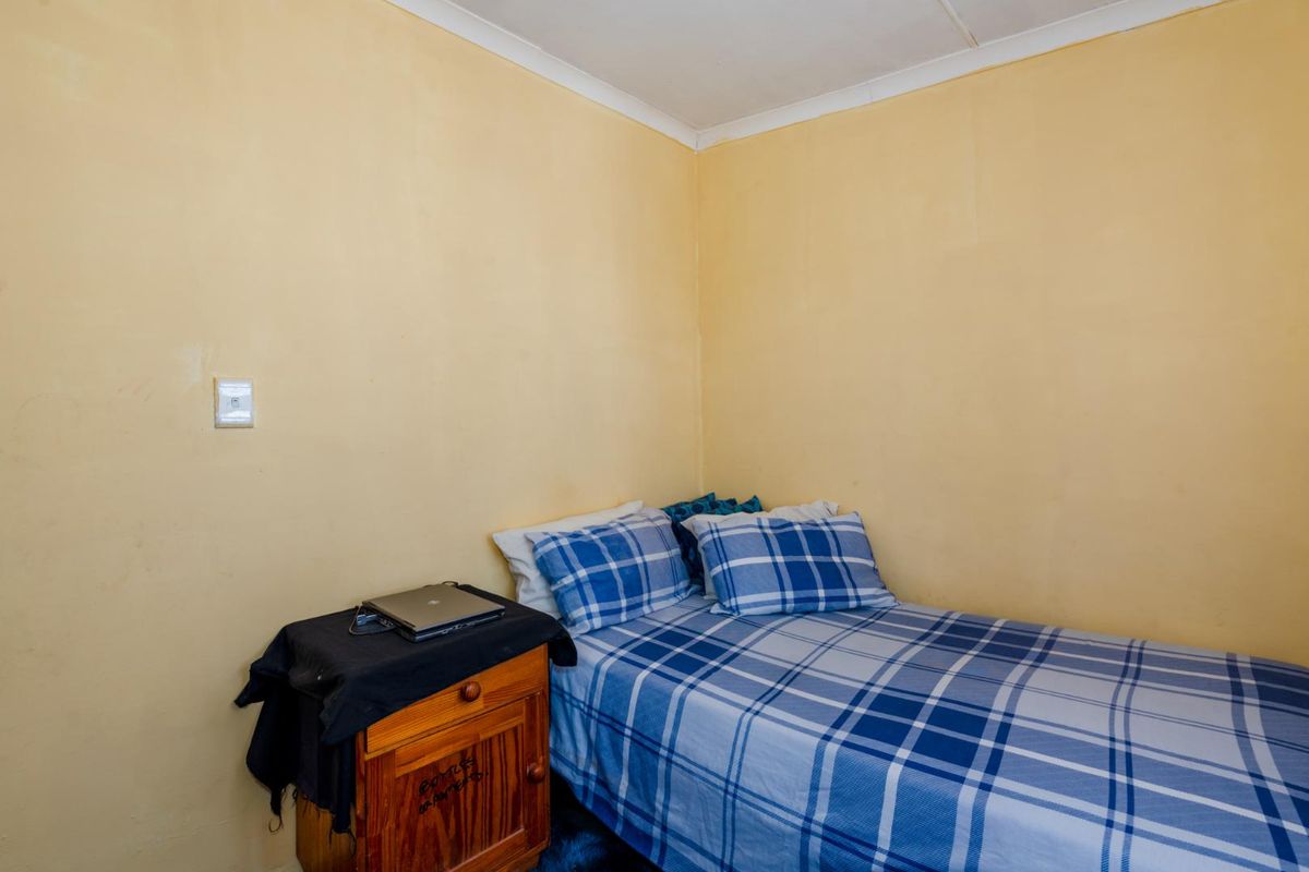 A compact bedroom featuring yellow painted walls and a simple ceiling cornice.