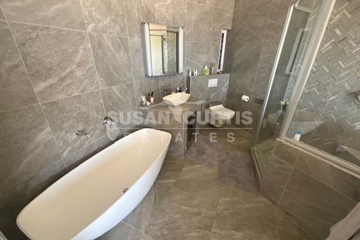 Modern bathroom featuring a freestanding bathtub, glass-enclosed shower, wall-mounted toilet, and contemporary stone-look wall and floor tiling.