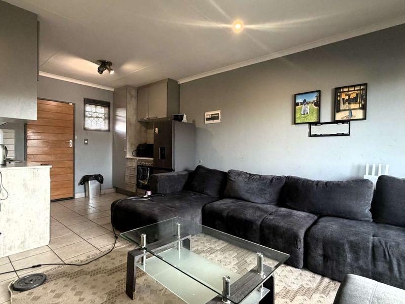Open-plan living area featuring tiled flooring, built-in kitchen cabinetry, and recessed lighting, creating a functional and connected living space.