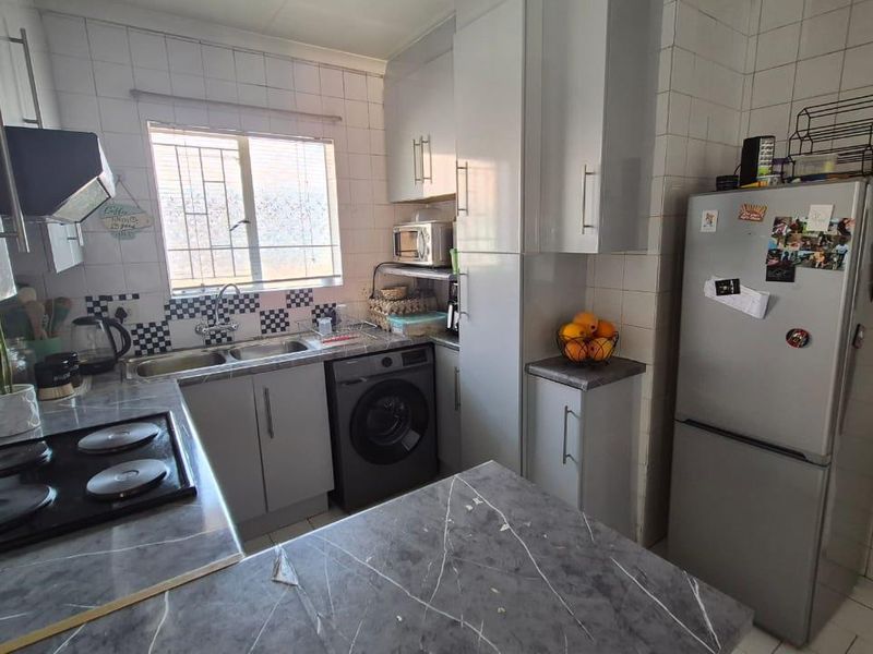 Compact kitchen featuring built-in cabinetry, laminate countertops, a double sink, and an electric hob with an extractor fan.