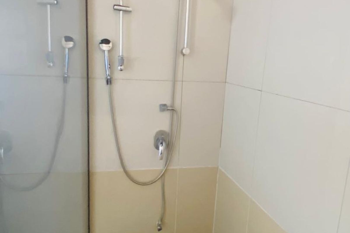 A clean shower enclosure featuring modern chrome shower fixtures, glass screen, and contrasting tiled wall and floor finishes.
