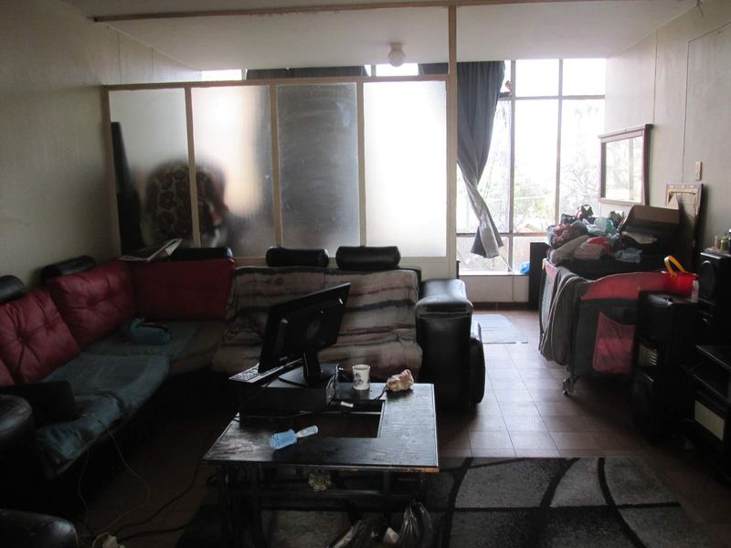 Living room area featuring large windows for natural light and a frosted glass partition, providing a functional layout with tiled flooring.