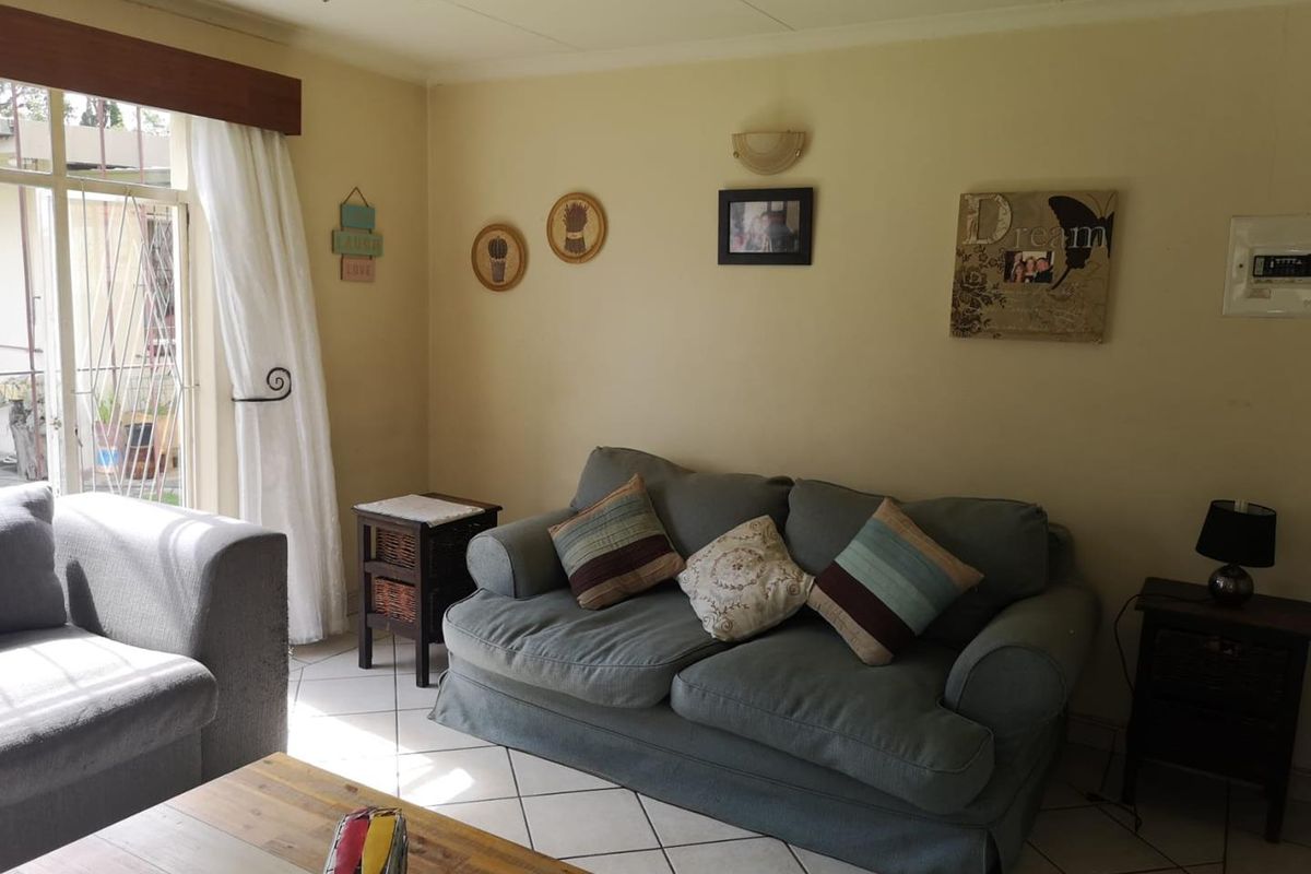 A comfortable living room featuring tiled flooring, a ceiling fan, and a sliding glass door providing natural light and access to the exterior.