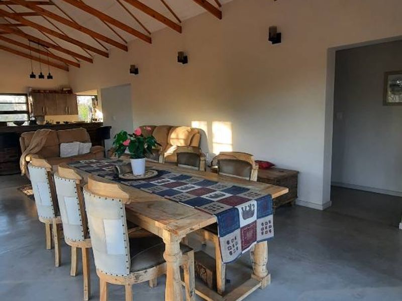 Spacious open-plan living and dining area featuring high vaulted ceilings with exposed timber trusses and polished concrete flooring throughout.