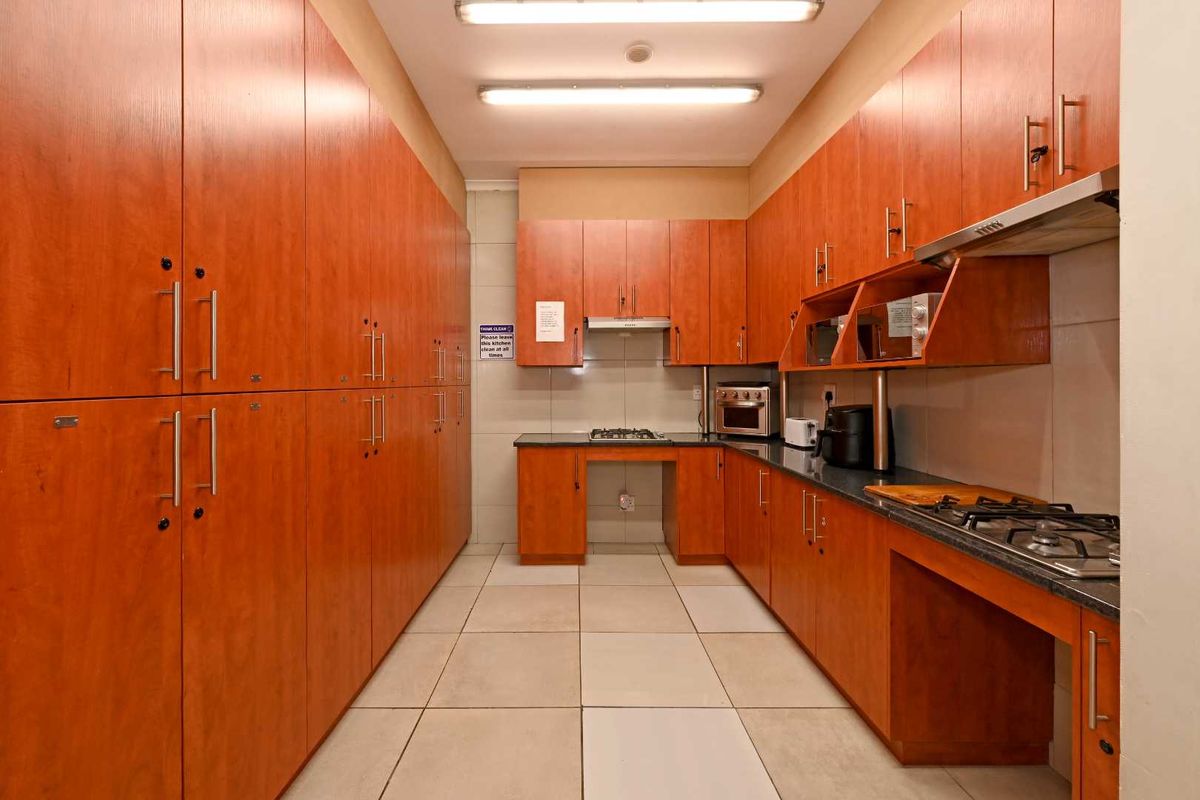 A functional galley-style kitchen featuring extensive wood-finish cabinetry, granite countertops, and integrated gas hobs with overhead extractor fans.