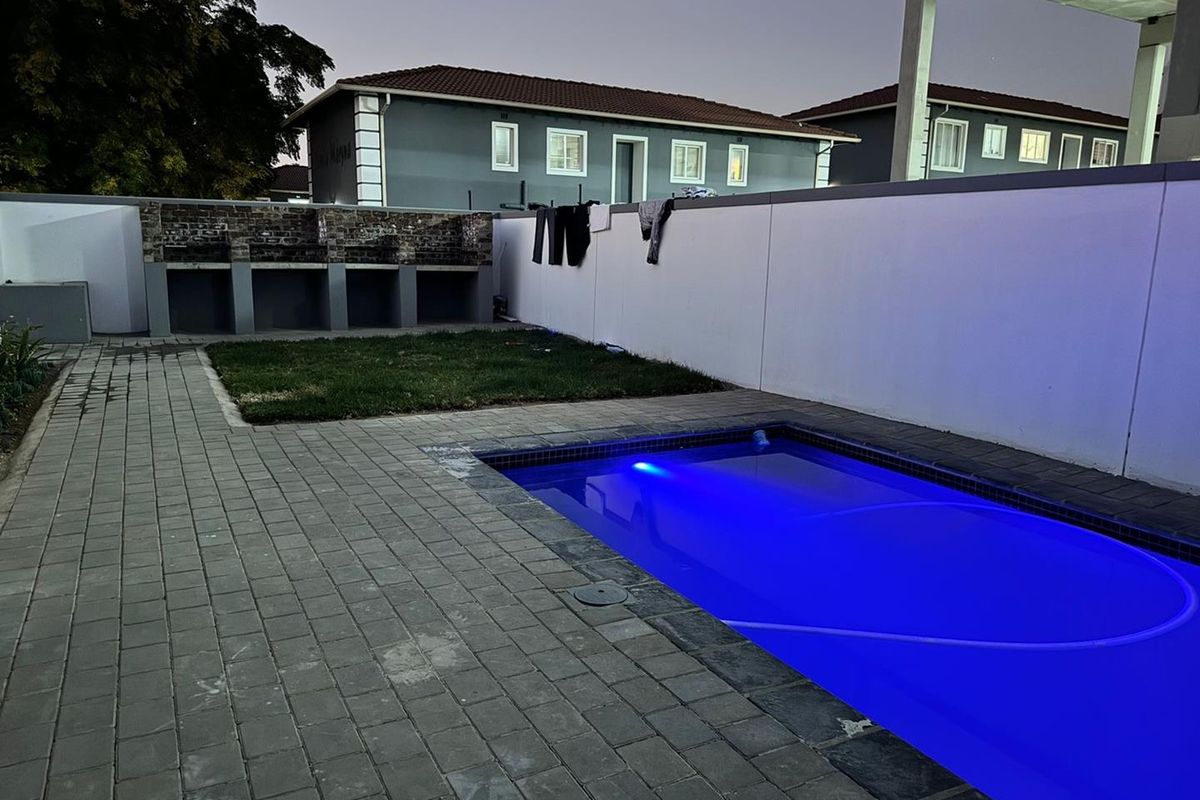 Outdoor pool area featuring a swimming pool, paved surround, and a built-in brick braai facility against the boundary wall.