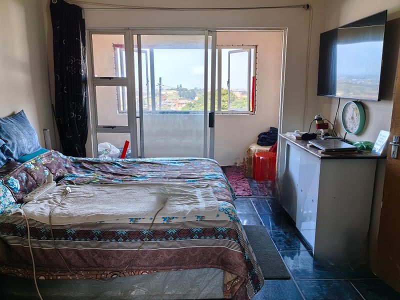 A bedroom featuring tiled flooring and a sliding glass door that opens to an enclosed balcony area with exterior views.
