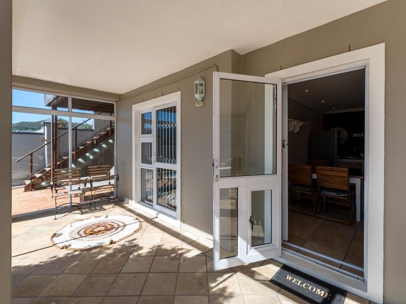 A covered patio area featuring tiled flooring, a glass security door, and direct access to the interior living space.