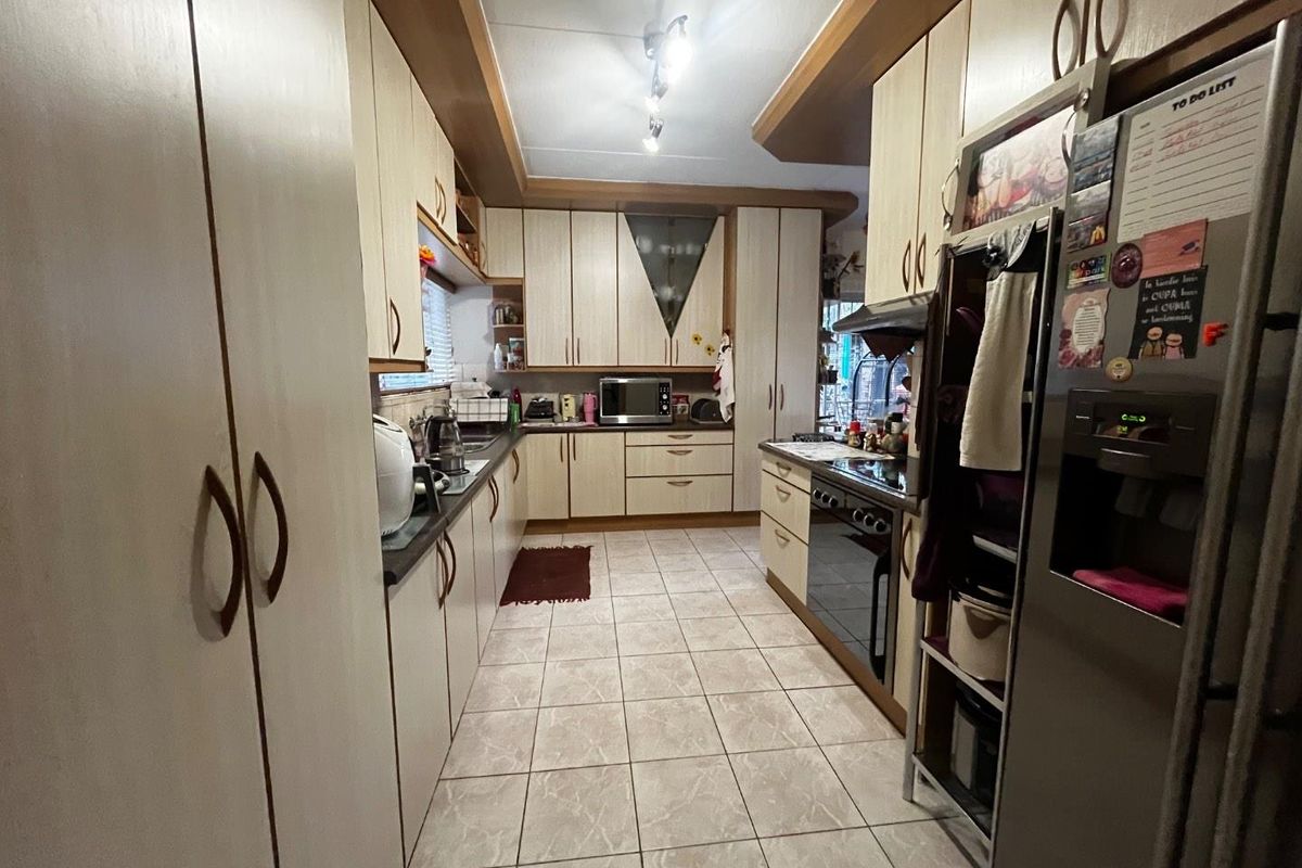 A functional galley-style kitchen featuring ample built-in cabinetry, tiled flooring, and integrated cooking appliances, offering a practical layout for daily meal preparation.