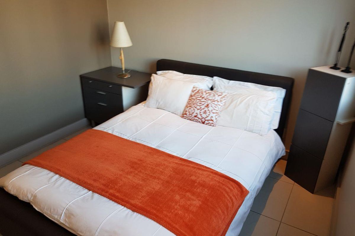 A functional bedroom featuring tiled flooring and neutral wall tones, providing a clean and simple living space.