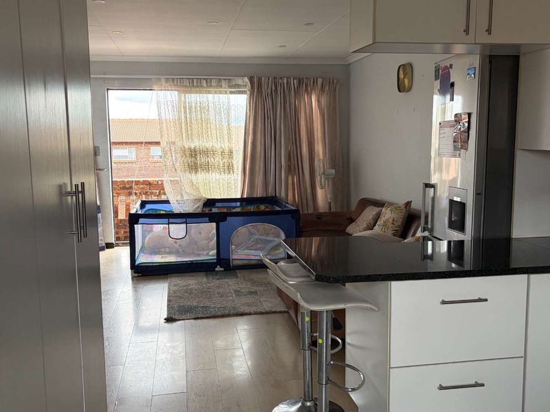 Open-plan living area featuring a modern kitchen with granite countertops and laminate flooring, leading directly to a balcony through a sliding glass door.