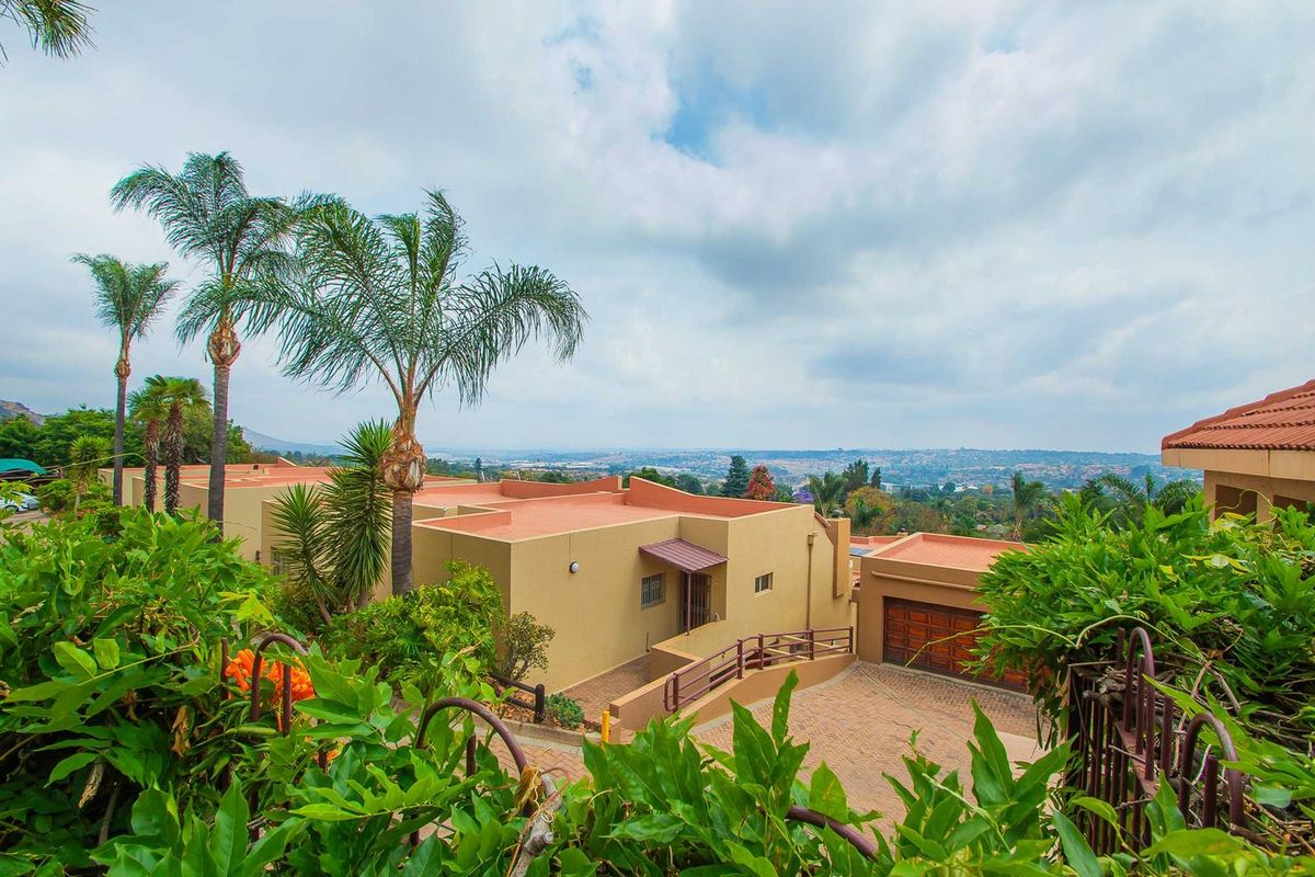 An elevated view of the apartment complex featuring paved driveways, garage access, and well-maintained exterior facades with a scenic landscape backdrop.