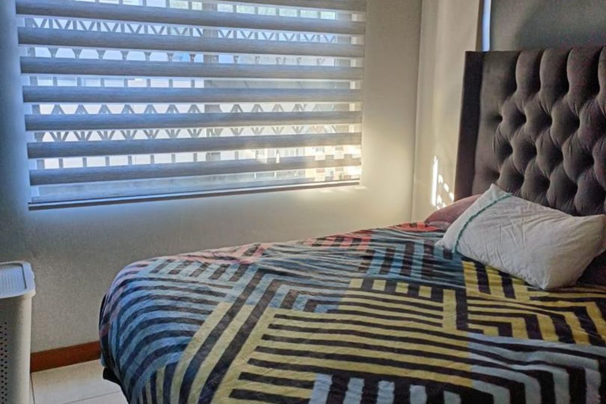 A bedroom featuring tiled flooring and a window fitted with modern zebra-style roller blinds.