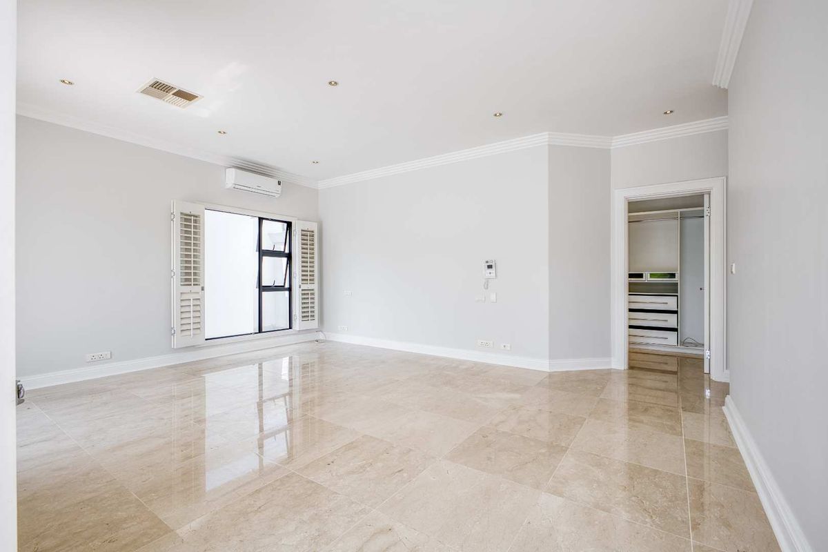 Spacious bedroom featuring polished stone flooring, recessed lighting, crown molding, a wall-mounted air conditioning unit, and an integrated walk-in closet.