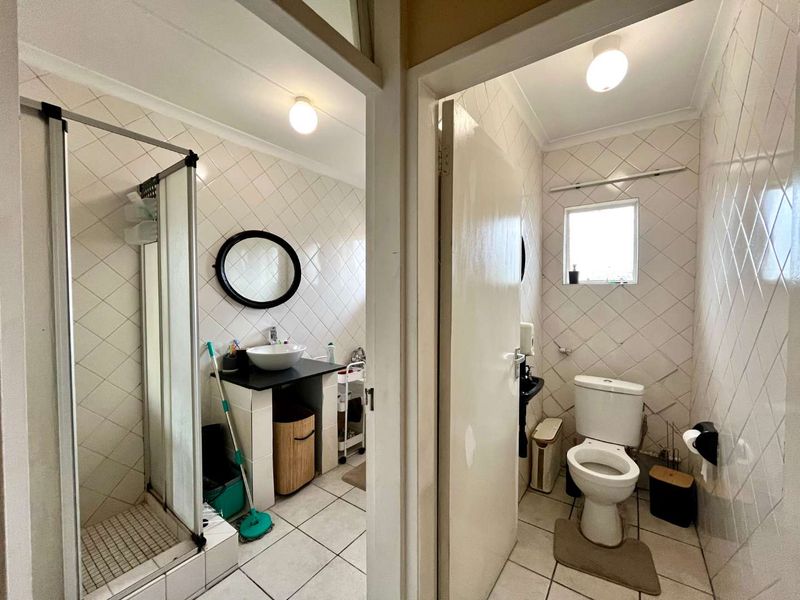 A functional bathroom featuring a separate shower enclosure, vessel sink vanity, and a private toilet area with tiled finishes throughout.
