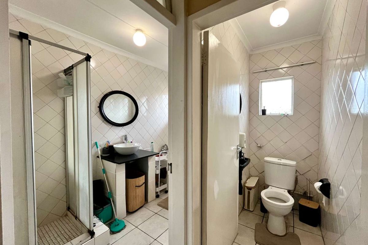 A functional bathroom featuring a separate shower enclosure, vessel sink vanity, and a private toilet area with tiled finishes throughout.