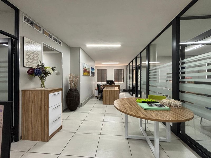 A modern office space featuring glass partition walls, tiled flooring, and integrated air conditioning, providing a professional and well-lit work environment.