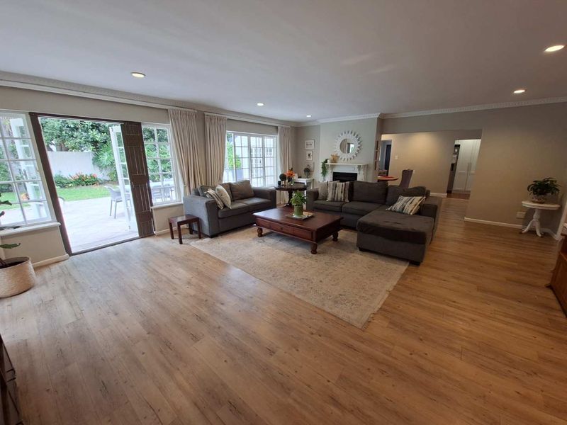 Spacious living room featuring laminate flooring, recessed lighting, crown molding, and a fireplace, with direct access to the outdoor patio area.