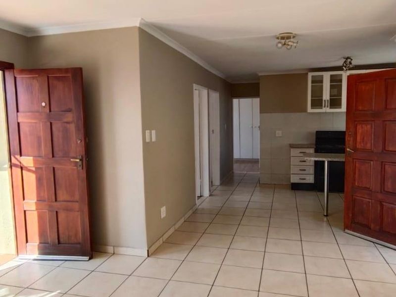 Open plan living area featuring tiled flooring, neutral walls, and a functional kitchen space with built-in cabinetry and counter.