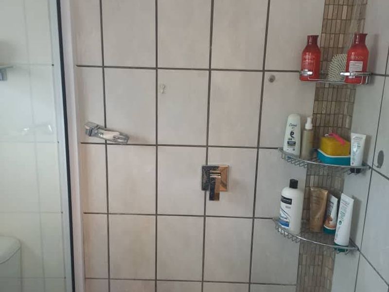A functional shower enclosure featuring tiled walls with a decorative mosaic accent strip and a glass door.