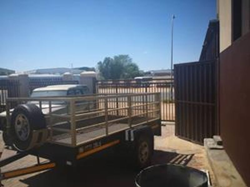 Exterior view of the industrial property entrance featuring a metal security gate and paved driveway area.