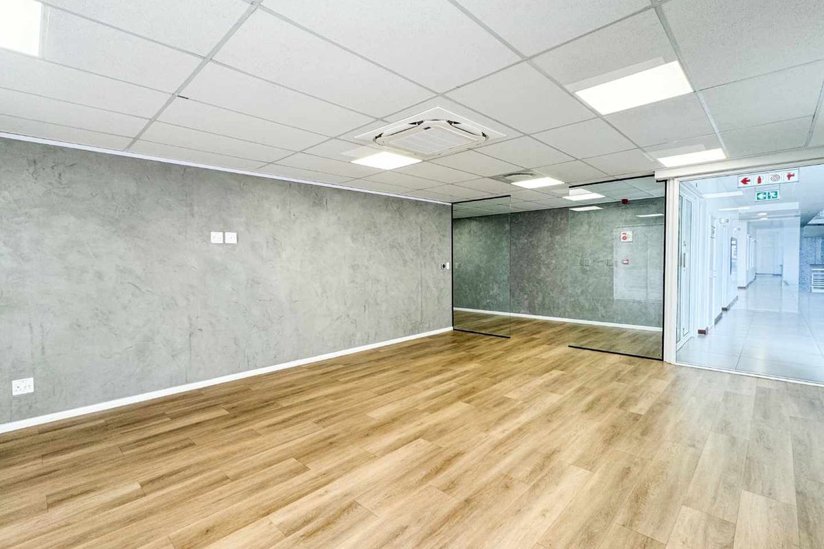 Modern, open-plan office space featuring high-quality laminate flooring, a textured feature wall, glass partitioning, and integrated cassette air conditioning.
