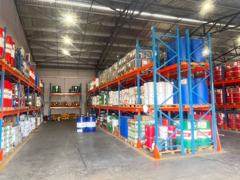 A spacious industrial warehouse facility featuring extensive steel racking systems, concrete flooring, and high-bay lighting, suitable for storage or distribution operations.