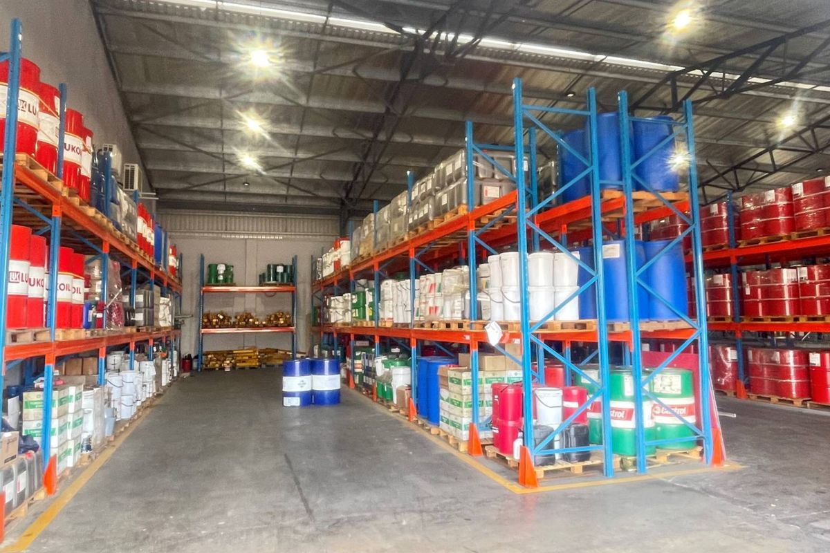 A spacious industrial warehouse facility featuring extensive steel racking systems, concrete flooring, and high-bay lighting, suitable for storage or distribution operations.