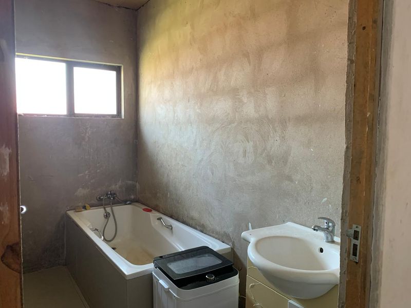 A bathroom in shell condition featuring a bathtub and basin, requiring wall finishes and general renovation to complete the space.