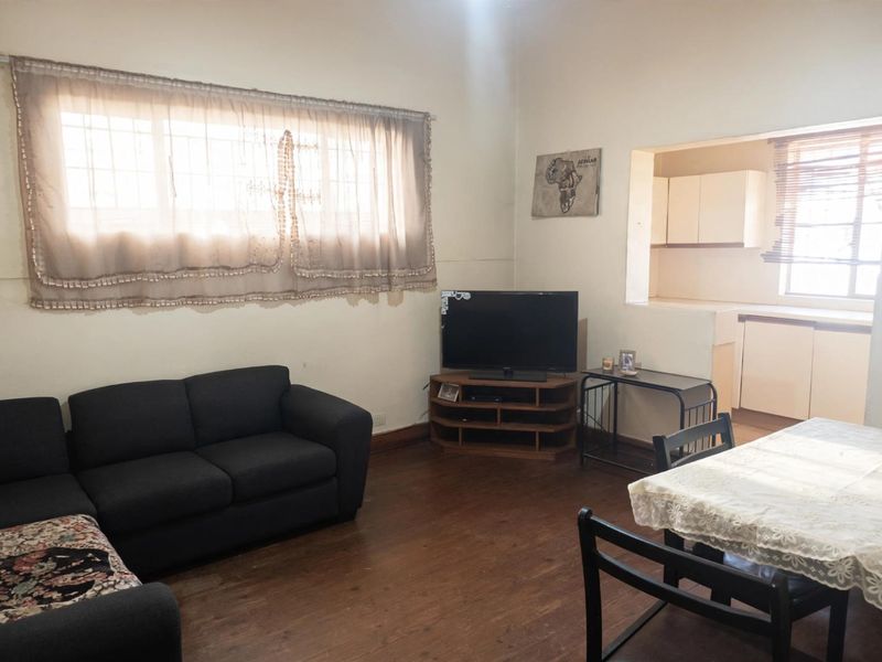 Open-plan living and dining area featuring laminate flooring and a convenient pass-through window connecting to the kitchen space.
