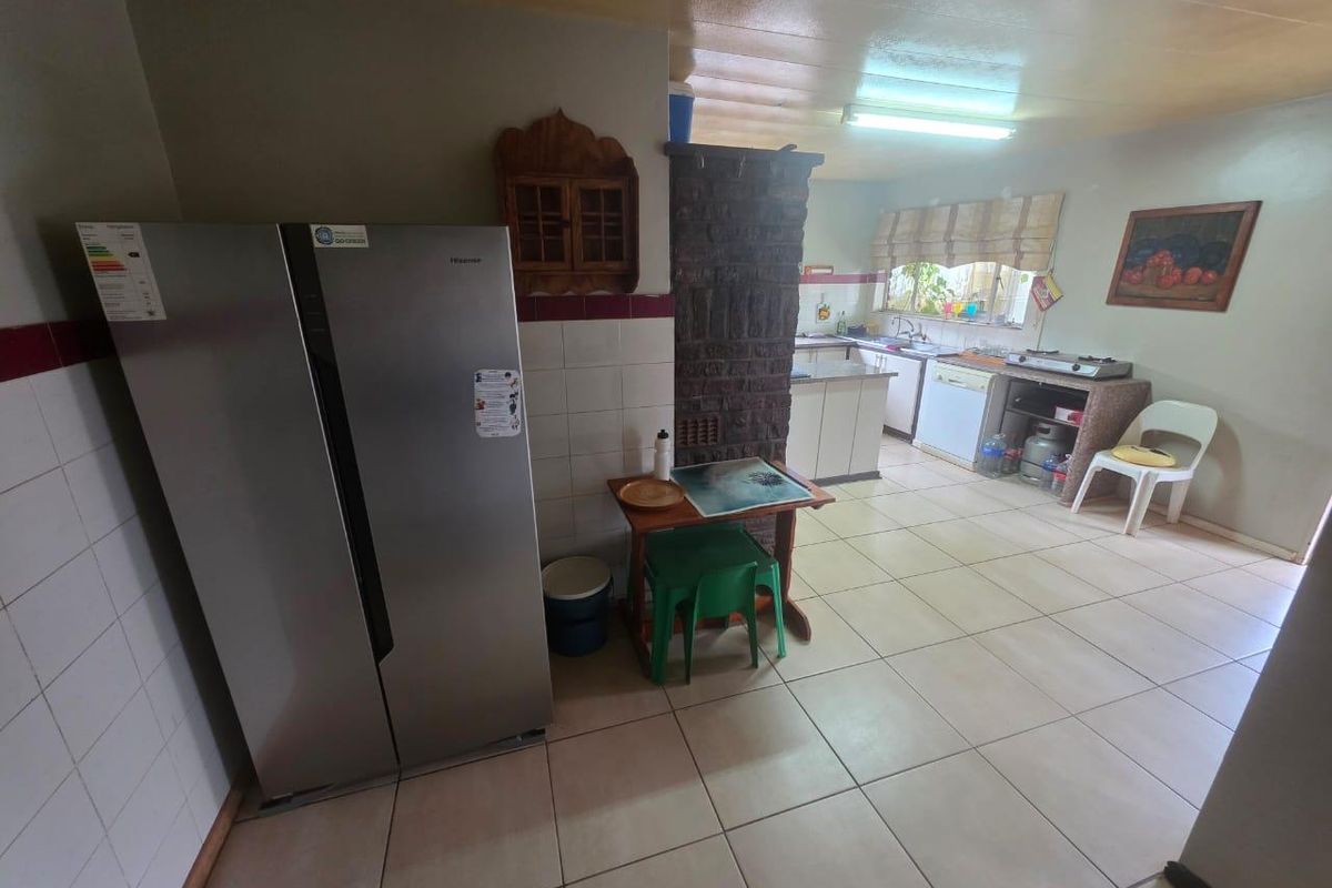 A functional kitchen featuring tiled flooring, built-in cabinetry, a central brick pillar, and a window above the sink area.