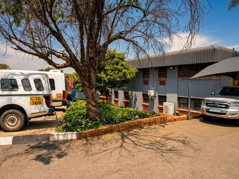 Front exterior view of the business premises featuring a paved driveway, covered parking area, and established landscaping.