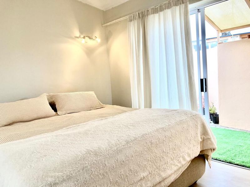 A bright bedroom featuring a sliding glass door that provides direct access to an outdoor patio area.