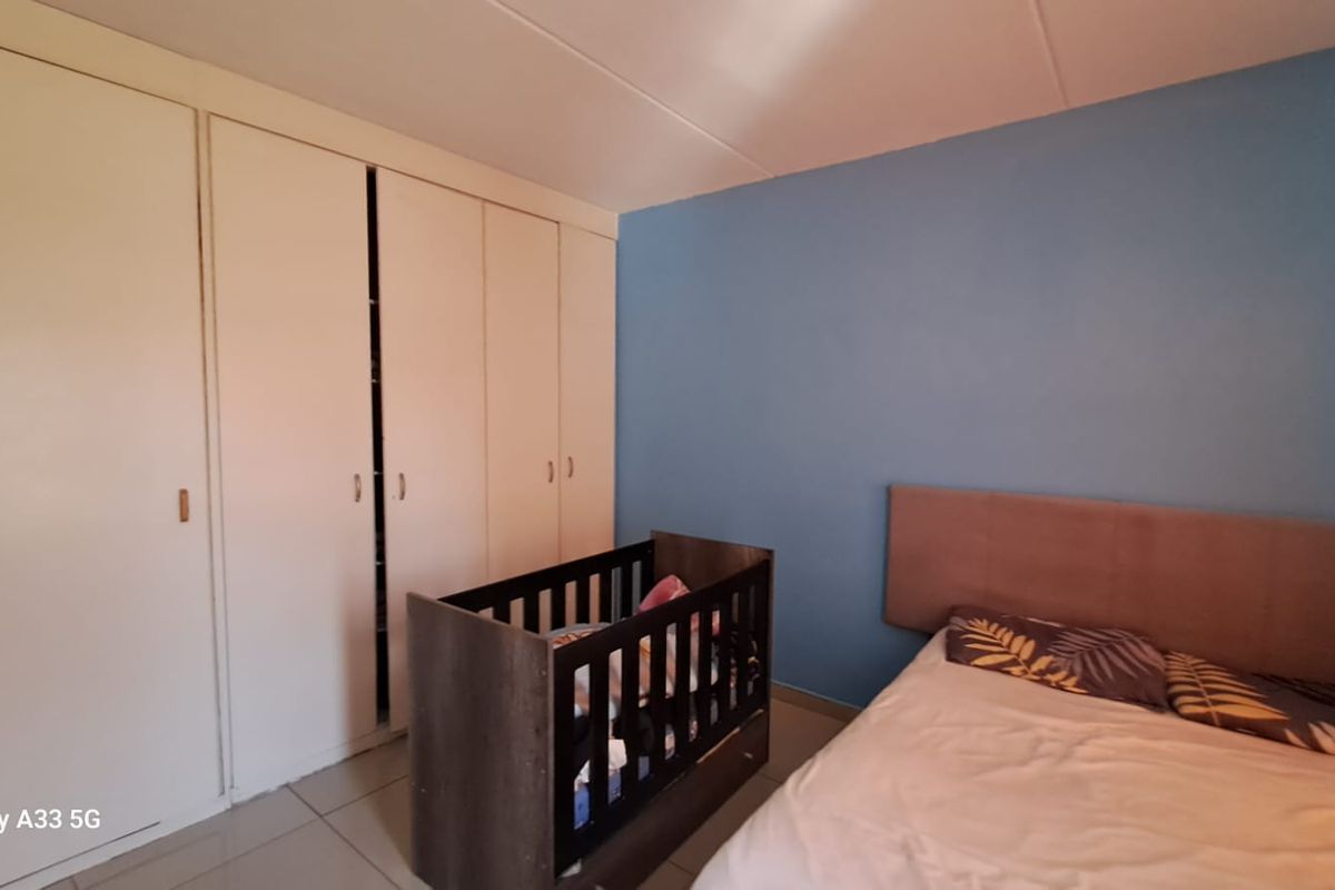 A bedroom featuring built-in floor-to-ceiling wardrobes and tiled flooring, with a blue accent wall.
