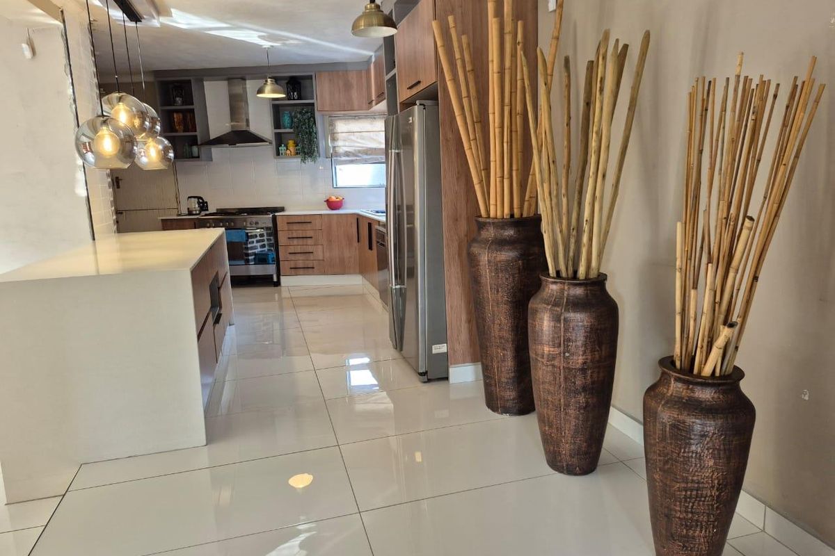 Modern kitchen featuring a central island, sleek cabinetry, integrated appliances, and polished tile flooring, creating a bright and functional culinary space.