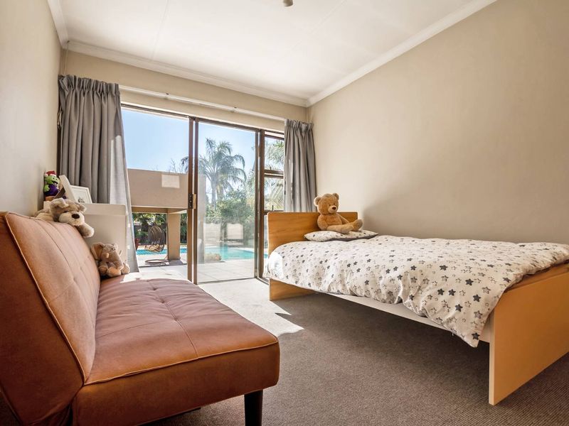 A bedroom featuring carpet flooring and a sliding glass door providing direct access to the outdoor pool area.