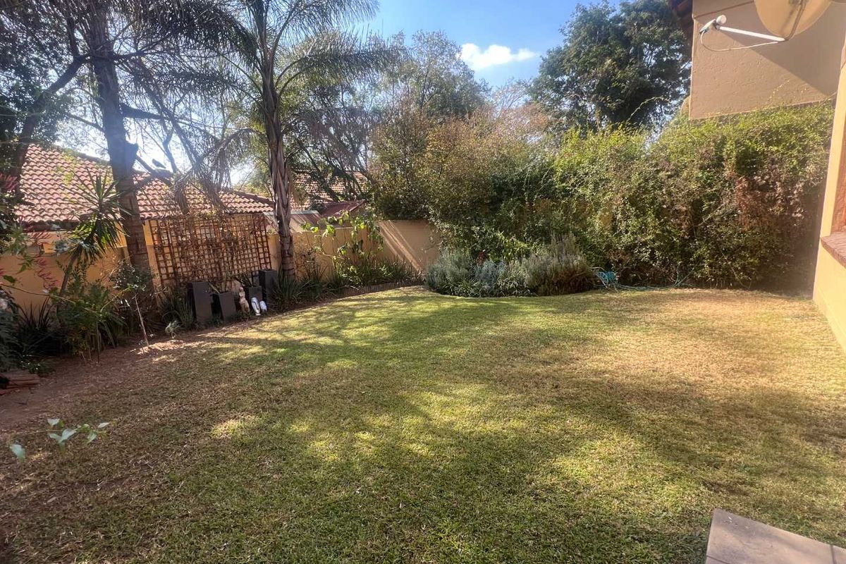 A private rear garden featuring a grass lawn, established perimeter landscaping, and boundary walls, providing a secluded outdoor space.