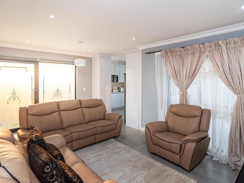 Open-plan living area featuring tiled floors, recessed lighting, and direct access to the kitchen, creating a bright and functional space.