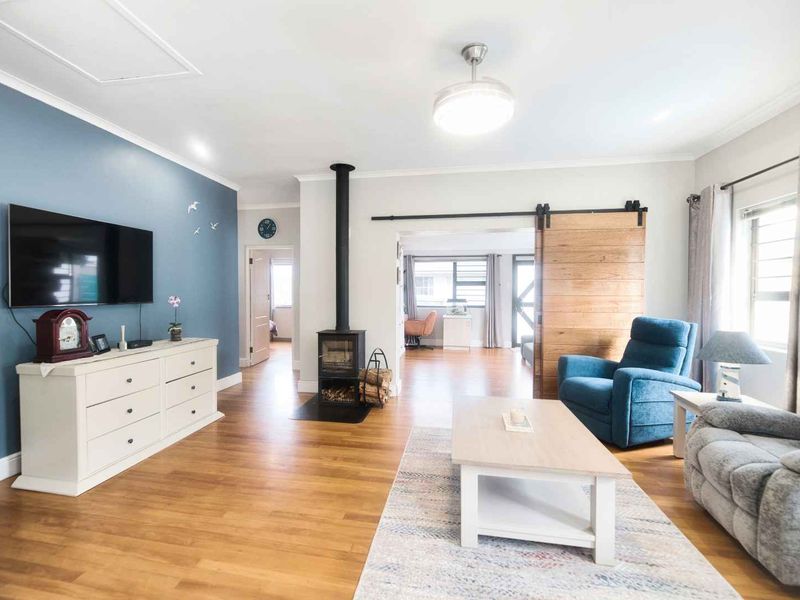 A bright living room featuring hardwood flooring, a wood-burning stove, and a sliding barn door leading to an adjacent space.
