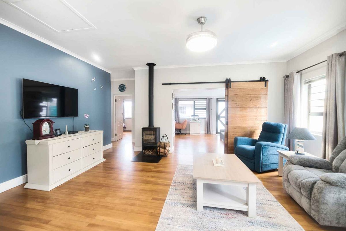 A bright living room featuring hardwood flooring, a wood-burning stove, and a sliding barn door leading to an adjacent space.