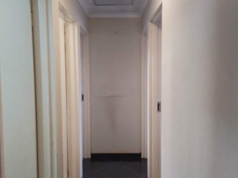A simple residential hallway featuring dark tiled flooring and neutral walls, providing access to multiple rooms.