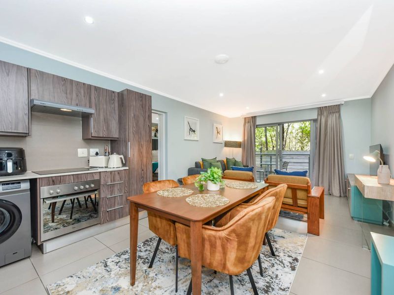 Modern open-plan living area featuring a well-equipped kitchen with built-in cabinetry, tiled floors, and seamless access to an outdoor patio through sliding glass doors.