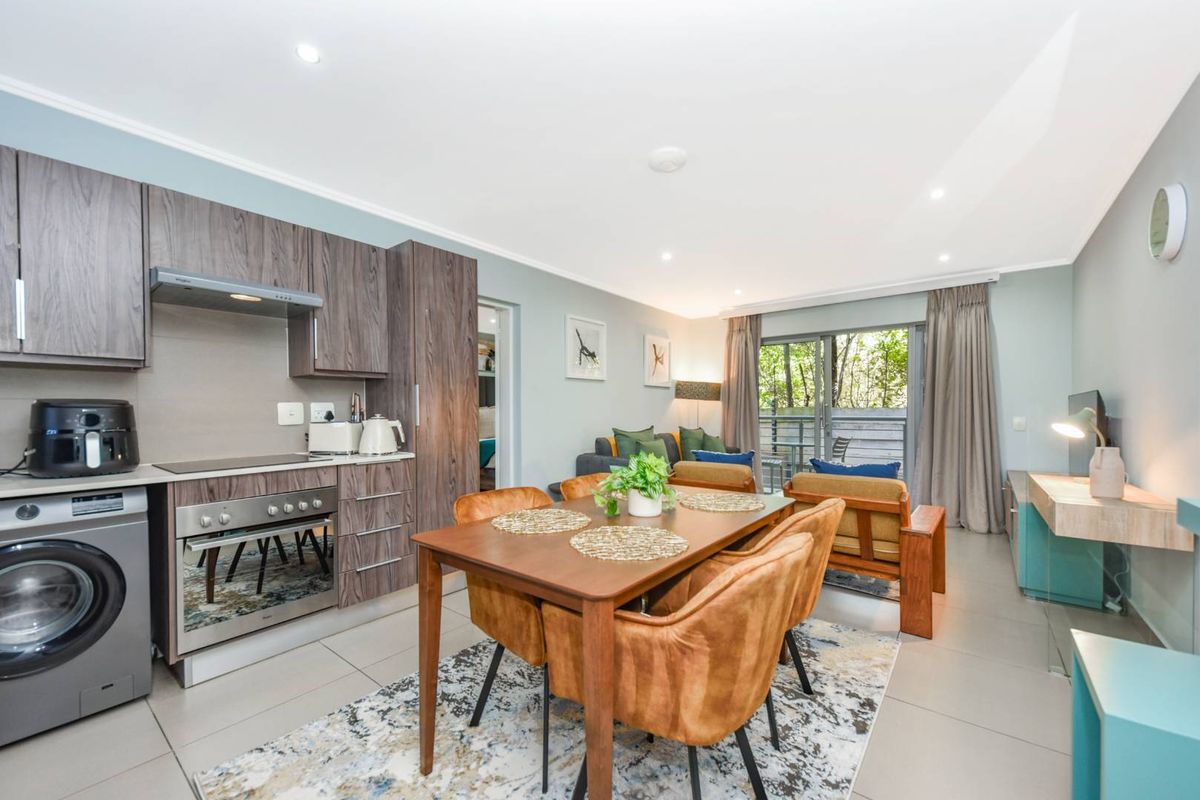 Modern open-plan living area featuring a well-equipped kitchen with built-in cabinetry, tiled floors, and seamless access to an outdoor patio through sliding glass doors.