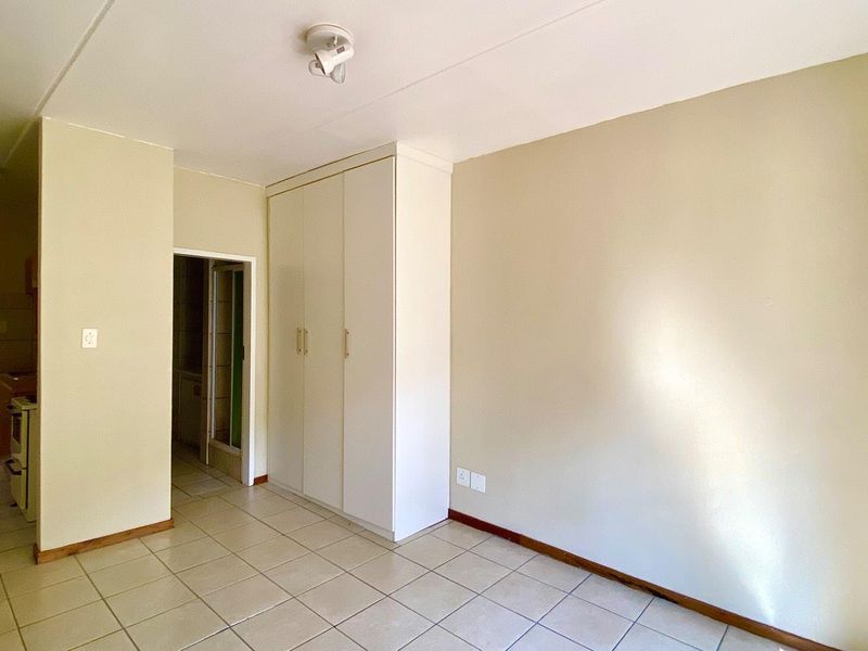 A clean, empty bedroom featuring neutral walls, tiled flooring, and a built-in wardrobe, offering a blank canvas for personalization.