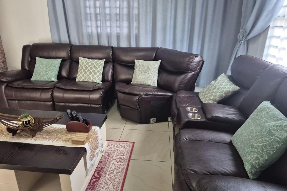 A comfortable living room area featuring tiled flooring and neutral curtains, providing a functional space for relaxation.