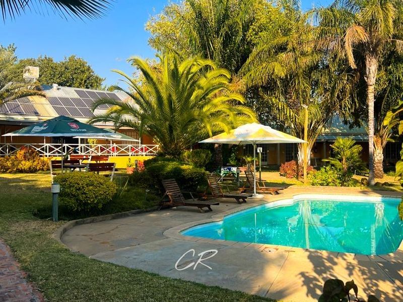 Outdoor pool area featuring a swimming pool, landscaped garden, and paved walkways, with solar panels visible on the building roof.