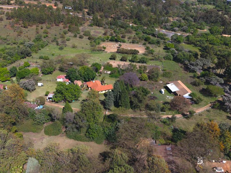 Aerial view of a large farm property featuring a main residence, multiple outbuildings, extensive grounds, and mature landscaping in a rural setting.